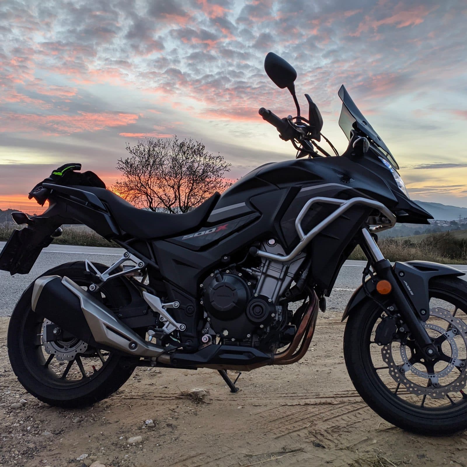 A Honda CB500X parked by a road at sunrise
